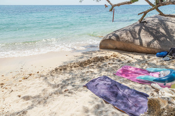 Towels for relaxation lying on sandy tropical beach under shade from tree summer vacation travel trip beach concept 