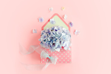 Beautiful bouquet of blue hydrangea in a floral envelope on a pink background. Flat lay, top view 
