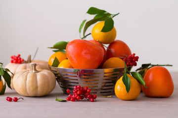 Fototapeta na wymiar Food. Tangerines, viburnum, pumpkin, persimmon in table