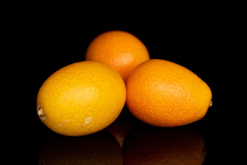 Group of three whole arranged tasty orange kumquat isolated on black glass