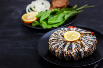Pilaf with hamsi anchovy fish. Traditional Turkish food - Kapama Pilav - on black wooden table.