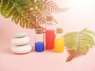 Flowers and plant extracts or perfume in small bottles on pink background. three small bubbles with red blue and yellow liquid, the concept of experiments and research. Space for text.