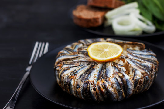 Pilaf with hamsi anchovy fish. Traditional Turkish food - Kapama Pilav - on black wooden table.
