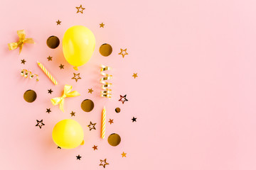 Gold confetti, balloons, streamers and decoration on a pink background. Colorful celebration, birthday background. Flat lay, top view 