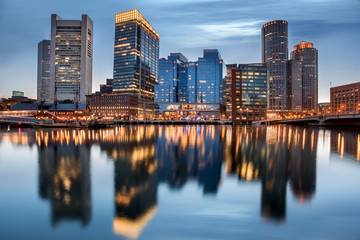 Fototapeta na wymiar Boston waterfront taken at dusk in a cloudy evening with skyscrapers reflected in the bay water, Massachusetts, USA