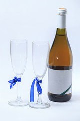 A bottle of sparkling wine and two glasses with ribbons