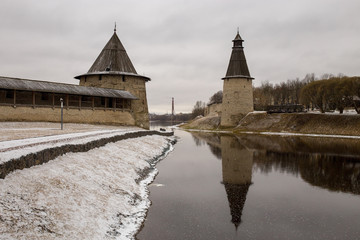 Plakat The ancient medieval fortress is located on the river Bank. The fortress is covered with fallen snow. Pskov, Russia.