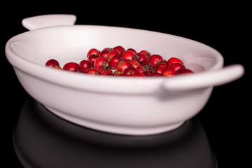 Lot of whole wild red rowanberry in small white ceramic bowl isolated on black glass