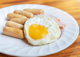 Close up fried egg and sausages with hams for breakfast on white plate traditional american breakfast food