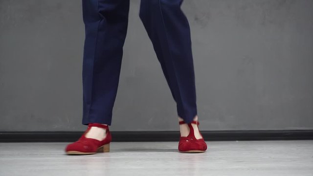 Girl dancing solo jazz swing dance. Dancer's legs close-up. Funny dance on grey background.