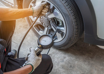 Close up mechanic inflating put air into the tyre and checking air pressure with gauge pressure in service station           - 306681337