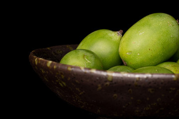 Lot of whole hardy green kiwi closeup in glazed bowl isolated on black glass
