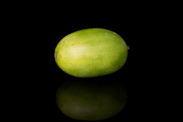 One whole hardy green kiwi isolated on black glass