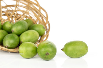 Lot of whole hardy green kiwi in round rattan bowl isolated on white background