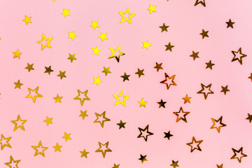 Confetti golden stars on pink background. Holiday backdrop. Flat lay, top view