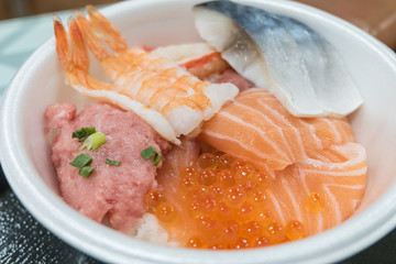 Sushi Donburi or Japanese rice bowl topped with fresh seafood sashimi at fish market