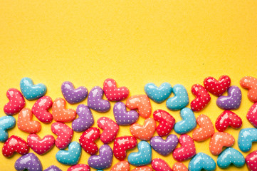 various colorful hearts lying on yellow paper like jolly colorful love background with copy space 