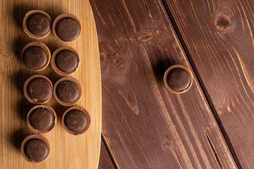 Lot of whole sweet brown toffee on bamboo cutting board flatlay on brown wood