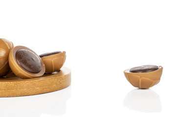 Lot of whole sweet brown toffee on round bamboo coaster isolated on white background