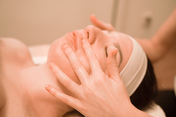 Beautiful young woman getting a face massage treatment at beauty salon