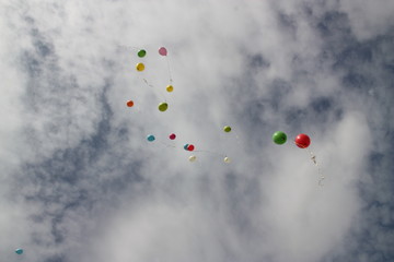 Background, texture, still life of multicolored balloons in the blue sky with white clouds.