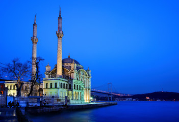 Fototapeta na wymiar The Mecidiye Mosque in Ortakoy in the blue hour. In the background one of the bridges of Bosphorus, that connects the 2 sides of Istanbul, Turkey.