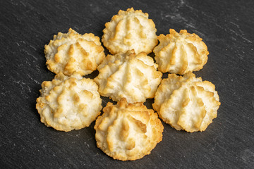 Group of seven whole homemade golden coconut biscuit on grey stone