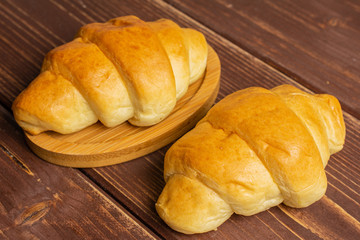 Group of two whole sweet golden mini croissant on brown wood