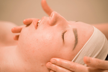 Beautiful young woman getting a face massage treatment at beauty salon