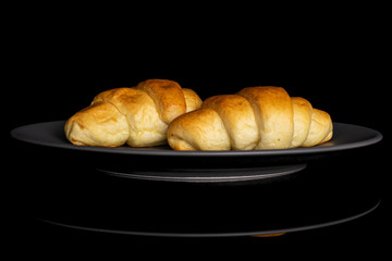 Group of two whole sweet golden mini croissant on gray ceramic plate isolated on black glass