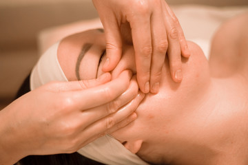 Beautiful young woman getting a face massage treatment at beauty salon