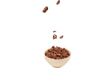 Chocolate corn flakes falling to the white bowl isolated on white. Motion.