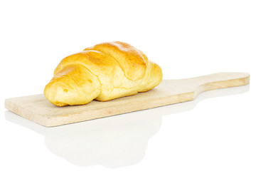 One whole sweet golden mini croissant on small wooden cutting board isolated on white background