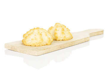 Group of two whole homemade golden coconut biscuit on small wooden cutting board isolated on white background