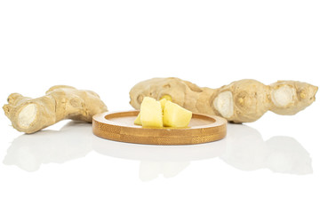 Group of two whole two pieces of fresh brown ginger on round bamboo coaster isolated on white background