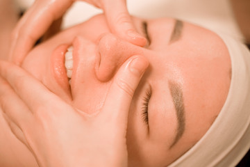 Beautiful young woman getting a face massage treatment at beauty salon step by step close up