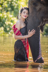 Women wearing thai dress hugging elephants