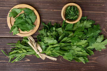 Lot of whole lot of pieces of fresh green parsley on round bamboo coaster in bamboo bowl with straw rope flatlay on brown wood