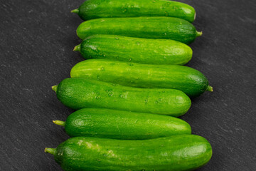 Lot of whole fresh green baby cucumber on grey stone