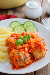 Pollock in tomato marinade with onions and carrots on a white plate with mashed potatoes, selective focus
