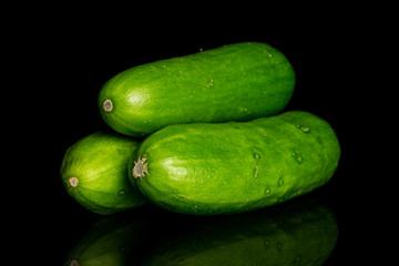 Group of three whole fresh green baby cucumber isolated on black glass