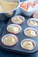 Raw muffins in a metal mold before baking, selective focus