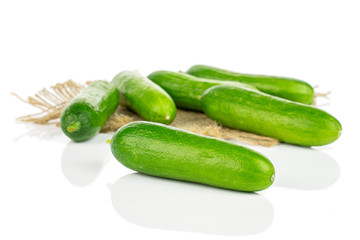 Lot of whole fresh green baby cucumber on natural sackcloth isolated on white background