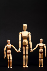 Conceptual image of a wooden manikin parent and children holding hands