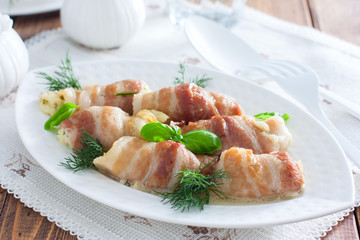 Oven bacon rolls with cheese baked on a white dish, horizontal