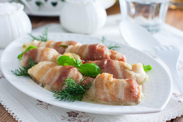 Oven bacon rolls with cheese baked on a white dish, horizontal