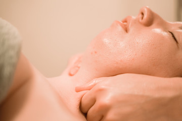 Fototapeta premium Beautiful young woman getting a face massage treatment at beauty salon step by step close up