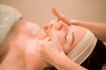 Beautiful young woman getting a face massage treatment at beauty salon