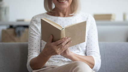 Woman sitting on couch closeup focus on hands holding book