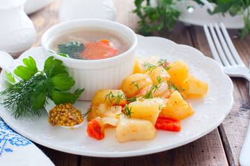 Baked sliced potatoes with carrots and onions on a white plate, horizontal